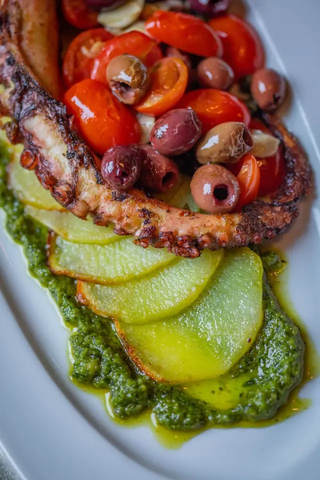 Succulent kokoretsi roasting on a skewer, capturing rich flavors and texture. - Photo by Engin…