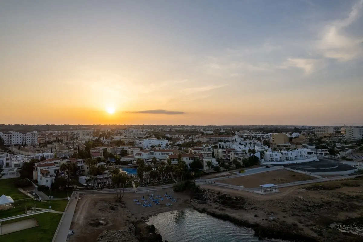Aerial view of Pernera, Famagusta at sunset, featuring a serene shoreline and vibrant townscape.…