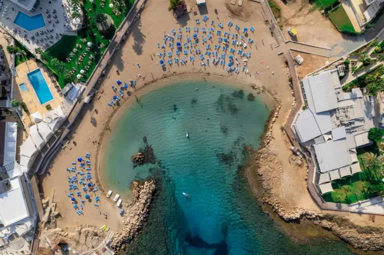 Stunning aerial shot of a beach resort in Paralimni, Cyprus, with sun loungers and clear blue…
