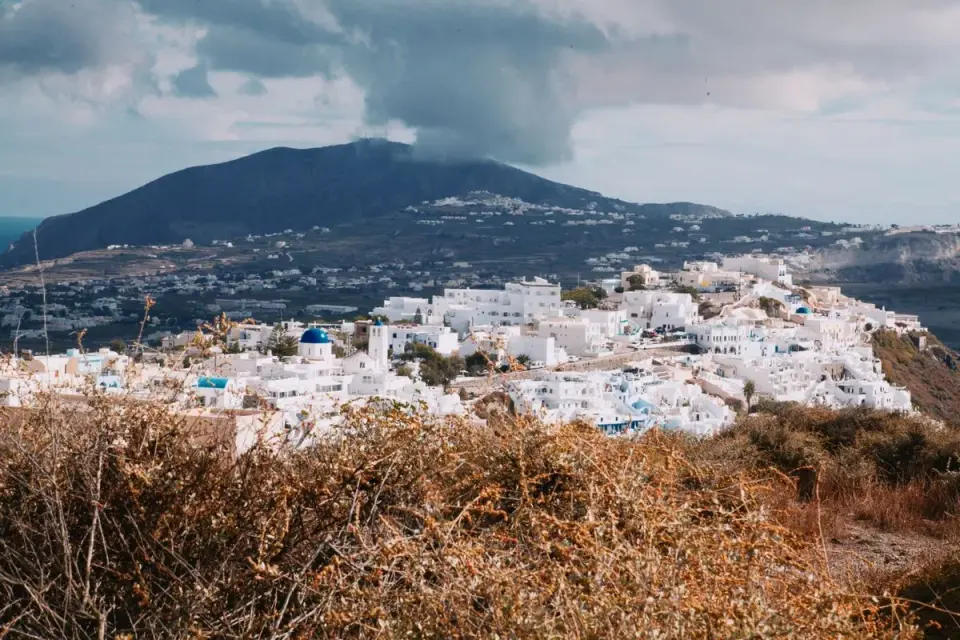 Experience the serene beauty of Santorini with iconic white buildings and scenic views. - Photo…