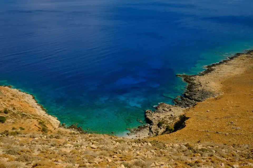 Stunning aerial view of a rocky coastline with clear blue water and arid terrain. - Photo by…