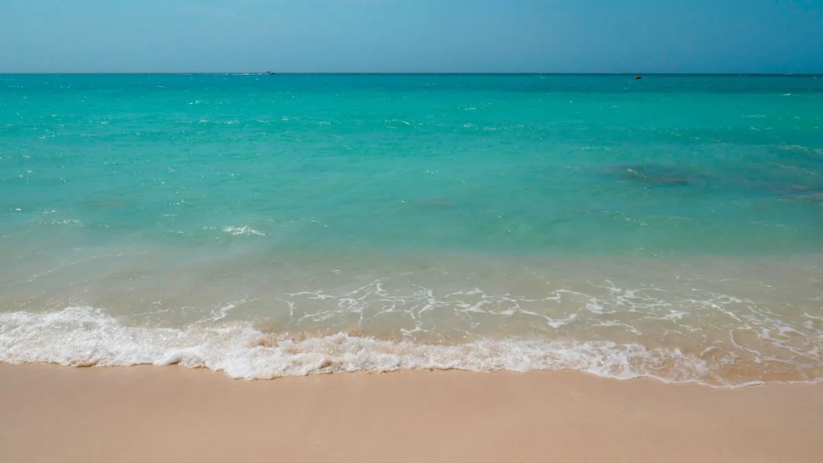 Serene beach scene with turquoise waves and sandy shore, perfect for relaxation imagery. - Photo…