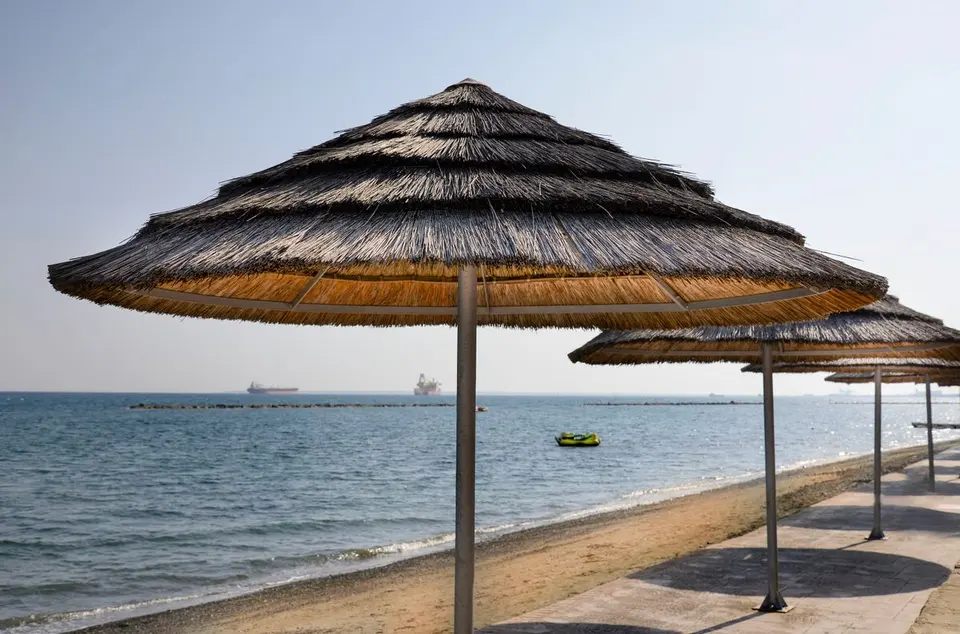 Tranquil beach setting with straw umbrellas along the Mediterranean coastline in Cyprus. - Photo…