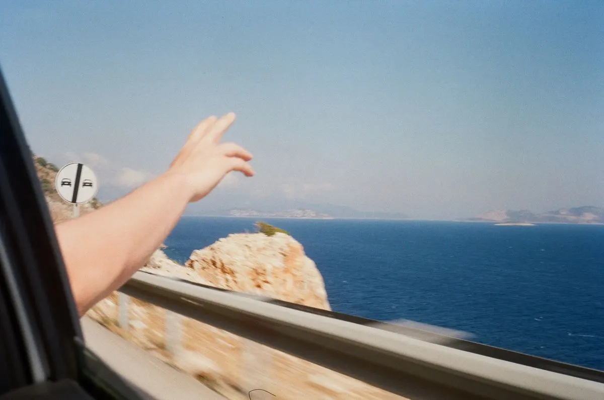 A car ride showcasing a hand making a peace sign against a stunning ocean view. - Photo by…