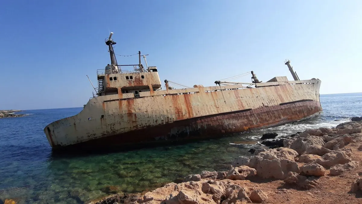 A rusting shipwreck stranded on the rocky coast of Paphos, Cyprus under clear skies. - Photo by…