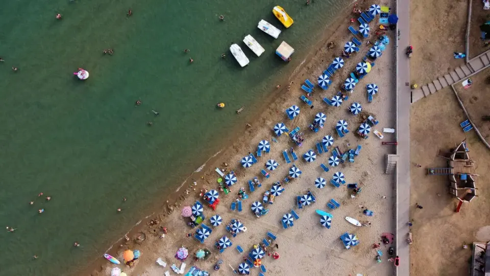 Aerial view of Lopar beach in Croatia, featuring colorful umbrellas and people enjoying the…