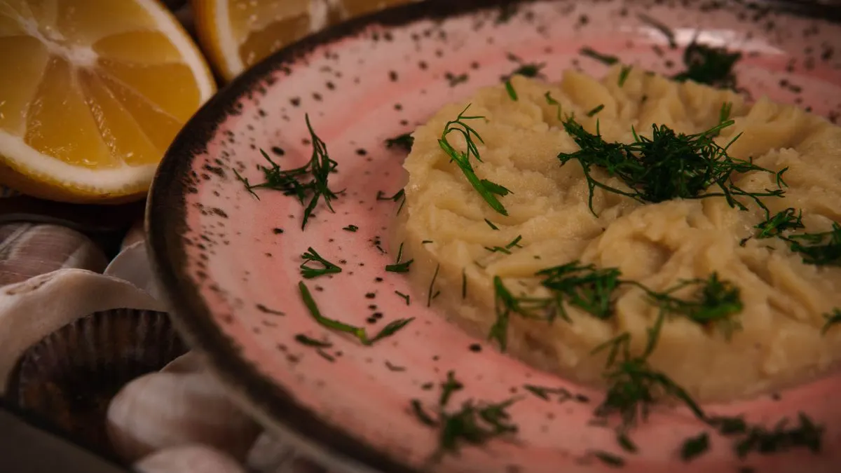 Close-up of a Mediterranean mezze dish garnished with fresh dill and lemon slices, captured in…