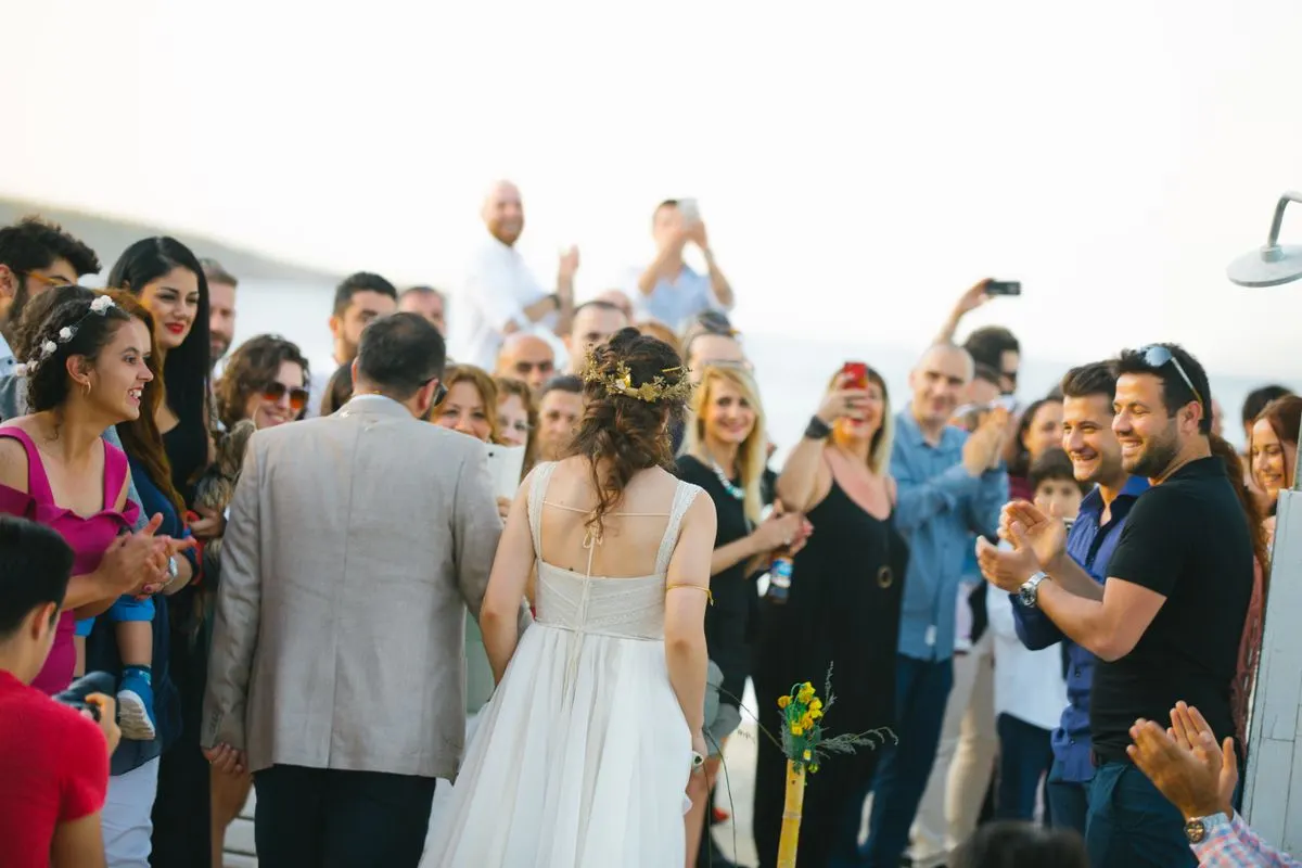 Cheerful outdoor wedding ceremony with a bride and groom surrounded by smiling guests. - Photo…