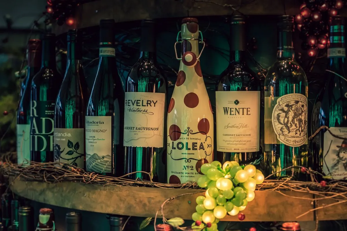 A showcase of assorted wine bottles displayed on a rustic shelf with decorative grapevine. -…