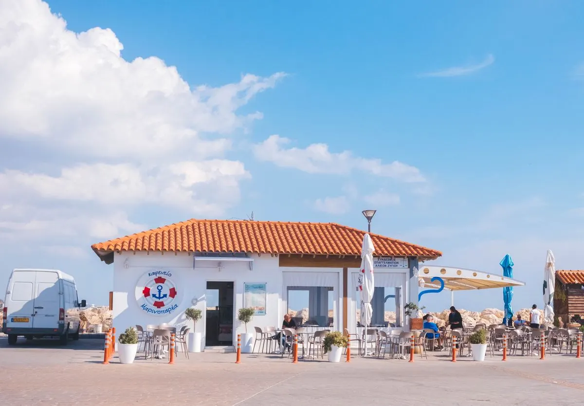 A cozy seaside cafe with outdoor seating under a bright blue sky in Cyprus. - Photo by Igor…
