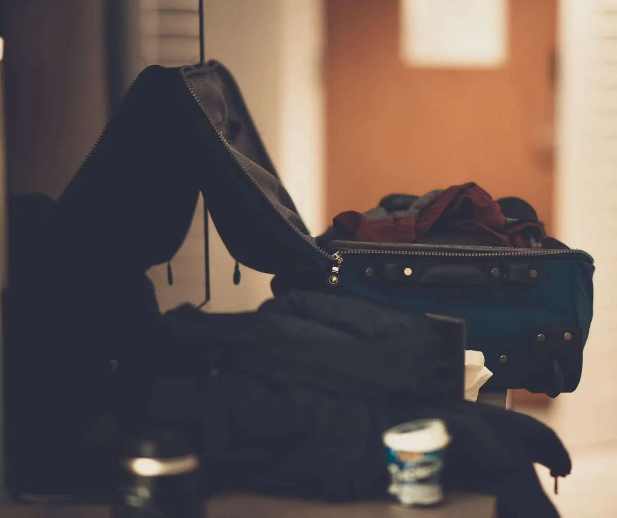 A warm-toned indoor image of an open suitcase with clothes, conveying travel readiness. - Photo…