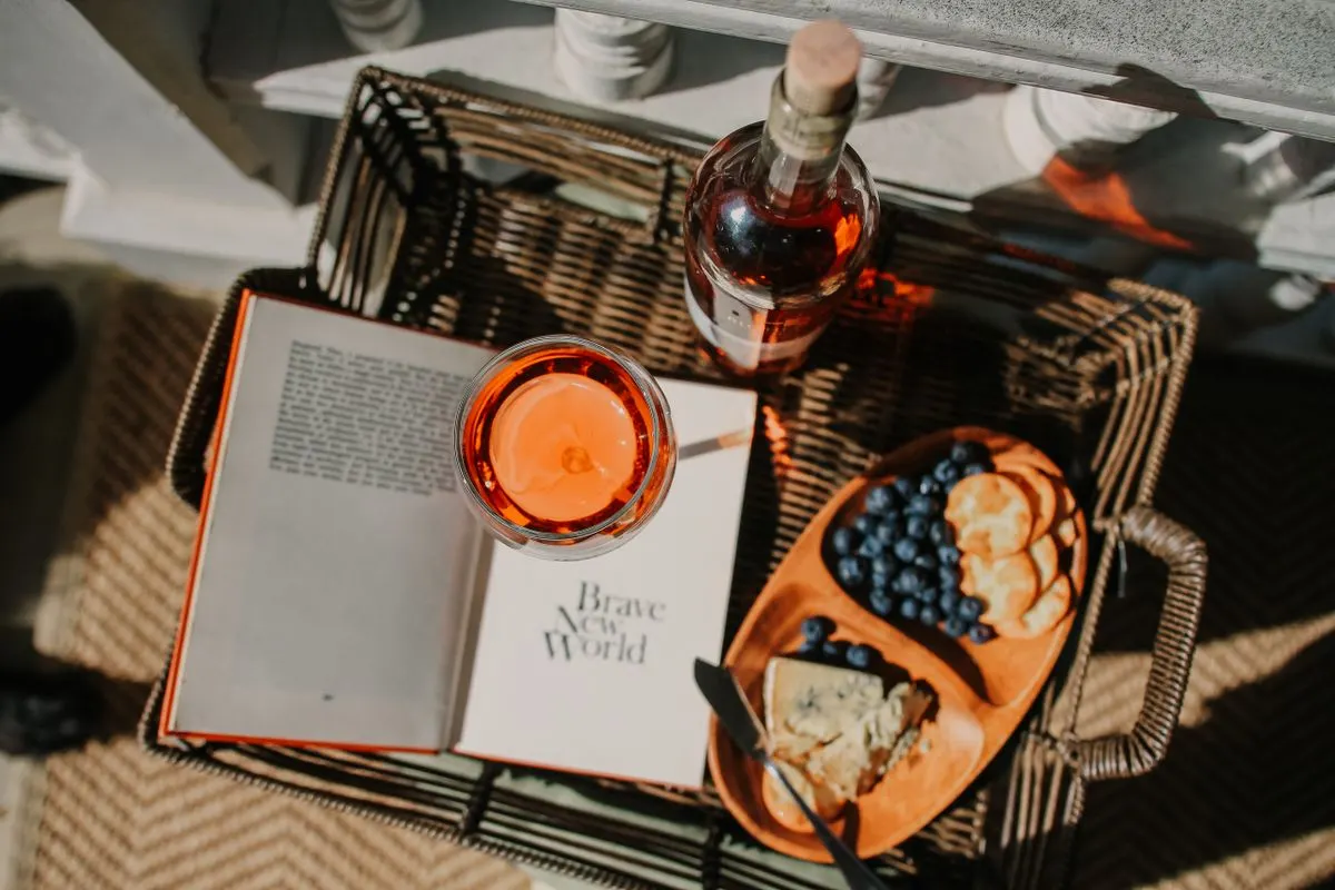 Relaxing picnic setup with wine, cheese, and a book under the sun. Perfect for leisure reading.…