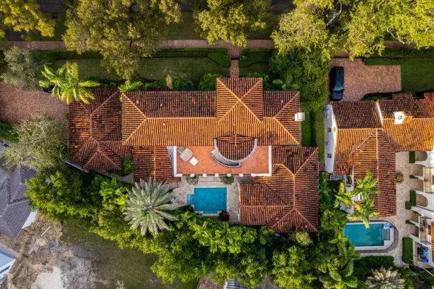 An aerial shot of a luxury home in Miami featuring a pool and lush greenery. - Photo by…