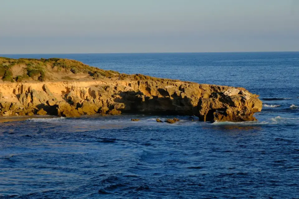 A beautiful coastal cliff reflecting on the ocean at sunset, capturing nature's serenity. -…