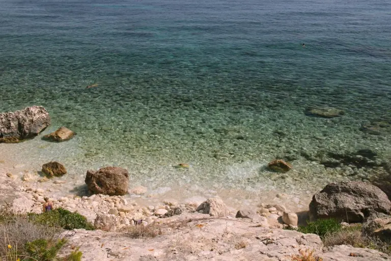 A tranquil rocky beach with clear turquoise waters under the summer sun, perfect for travel and…