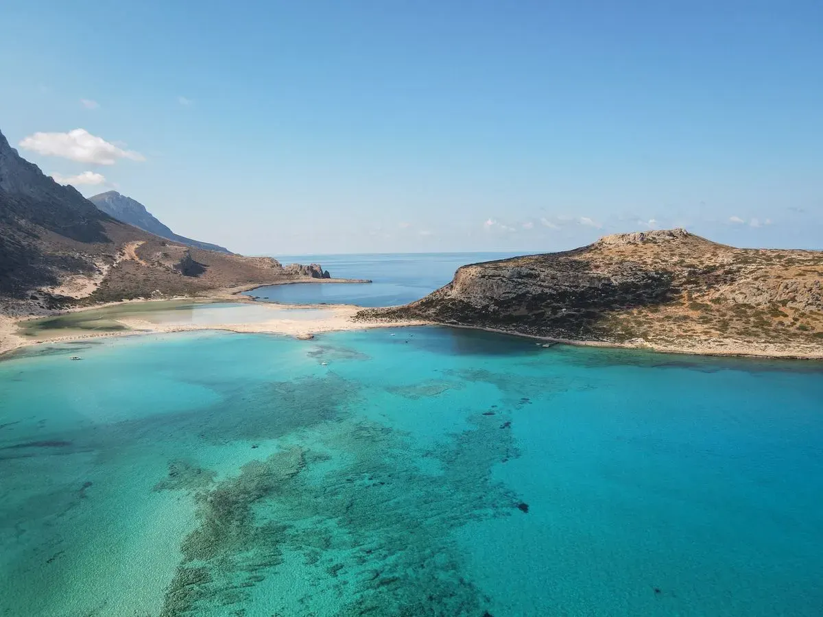 Breathtaking aerial capture of a turquoise lagoon and rugged island coastline under clear blue…