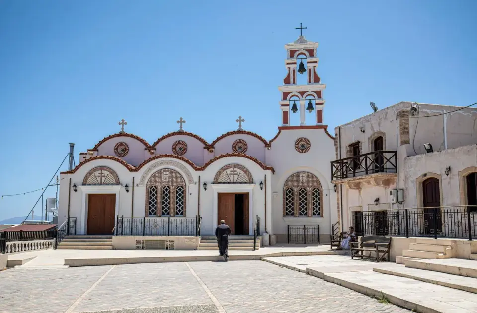 A picturesque view of a traditional Greek church in Hersonissos, Crete, under a clear blue sky.…