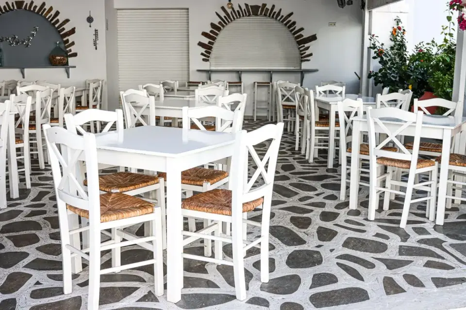 Traditional Greek cafe with white chairs and stone flooring in Naxos, Greece, ideal for tourism…