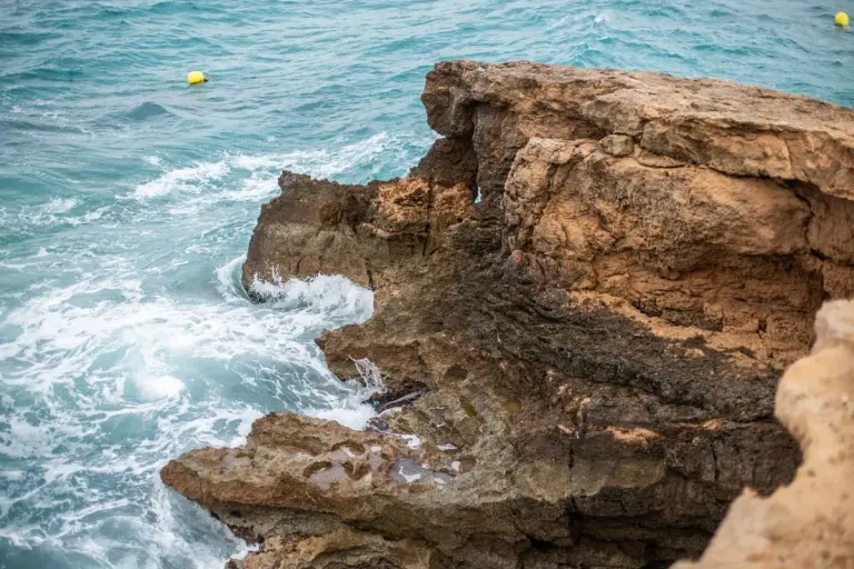Breathtaking view of Cala Tarida's rugged cliffs and blue Mediterranean Sea in Ibiza, Spain. -…