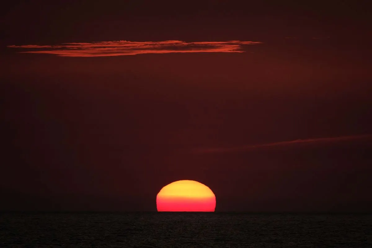 Breathtaking view of the sun setting over the Sardinian sea, creating a vibrant sky. - Photo by…