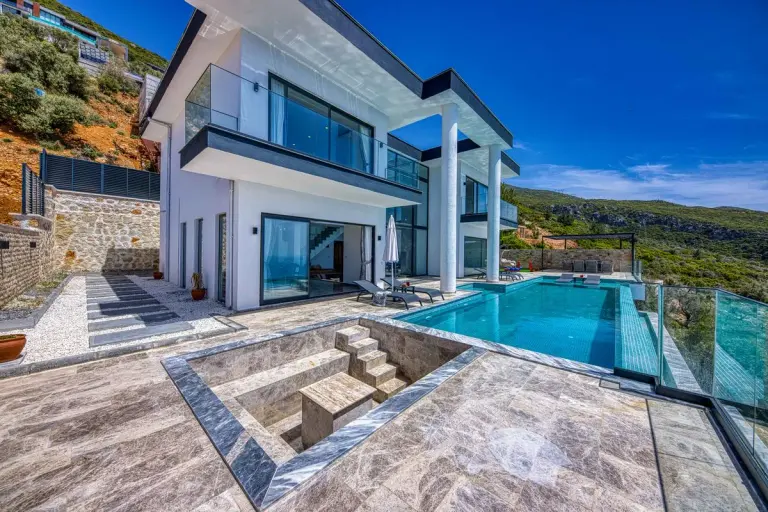 Stunning contemporary villa with glass, stone, and infinity pool; perfect for luxury living. -…