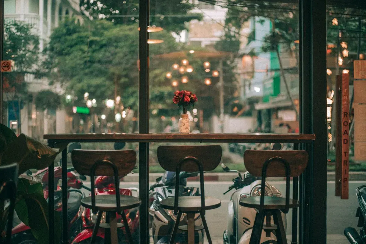 A cozy café in Ho Chi Minh City featuring a view of bustling streets with scooters. - Photo by…