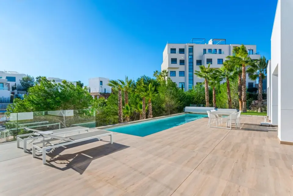 Elegant poolside terrace with palm trees and modern buildings in the background. - Photo by…