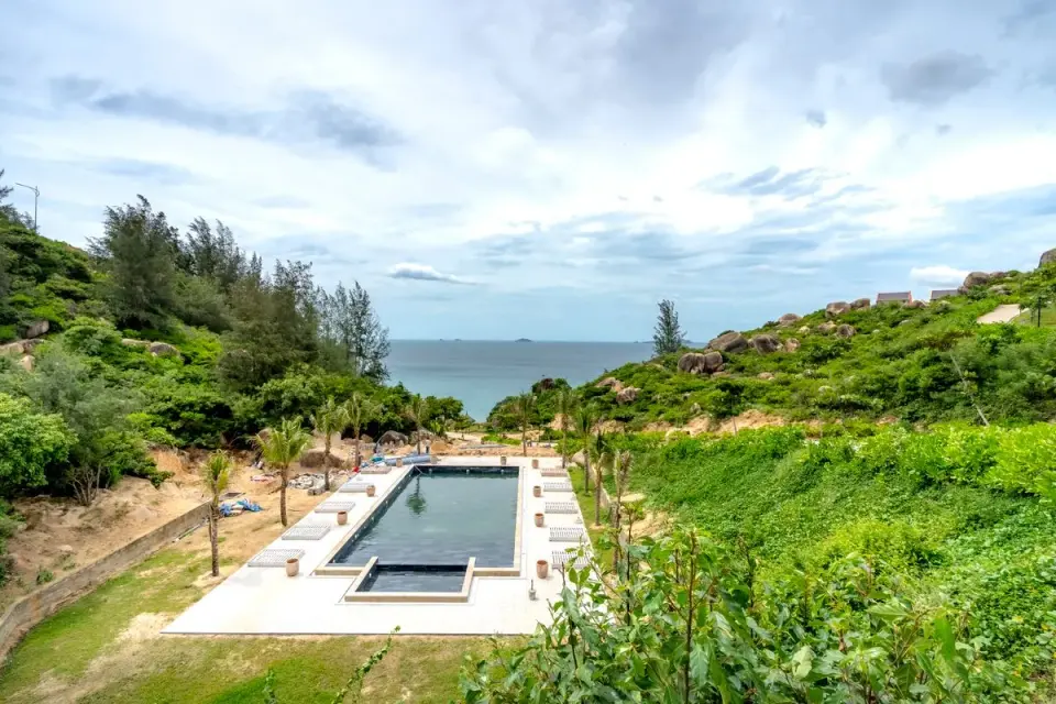 A stunning coastal pool surrounded by lush greenery and a serene ocean view. - Photo by Quang…