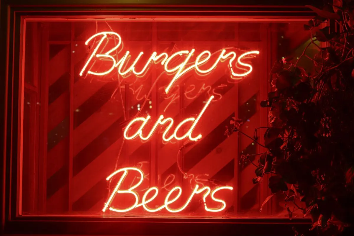 Vibrant red neon sign advertising 'Burgers and Beers' at night. - Photo by Boys in Bristol…