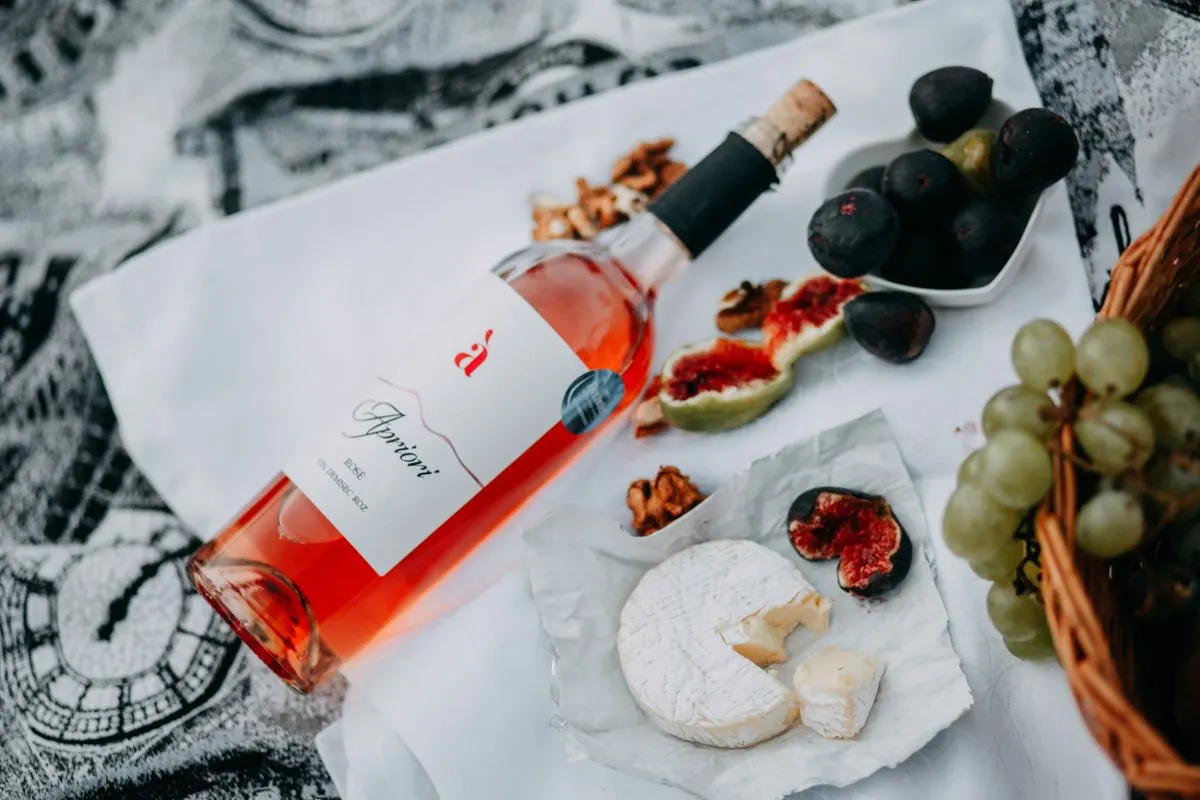 A stylish picnic scene with rosé wine, cheese, figs, and grapes, perfect for a luxurious outdoor…
