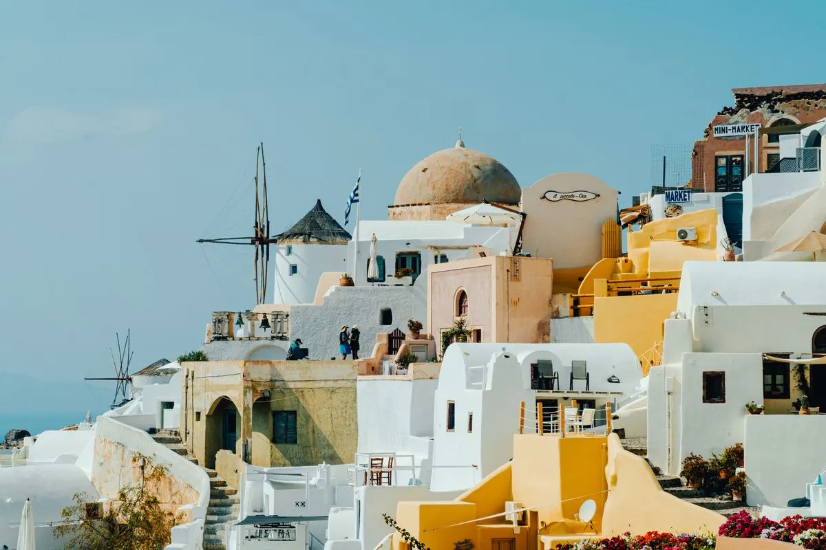 Charming view of traditional white and pastel buildings in Fira, Greece, against a clear summer…