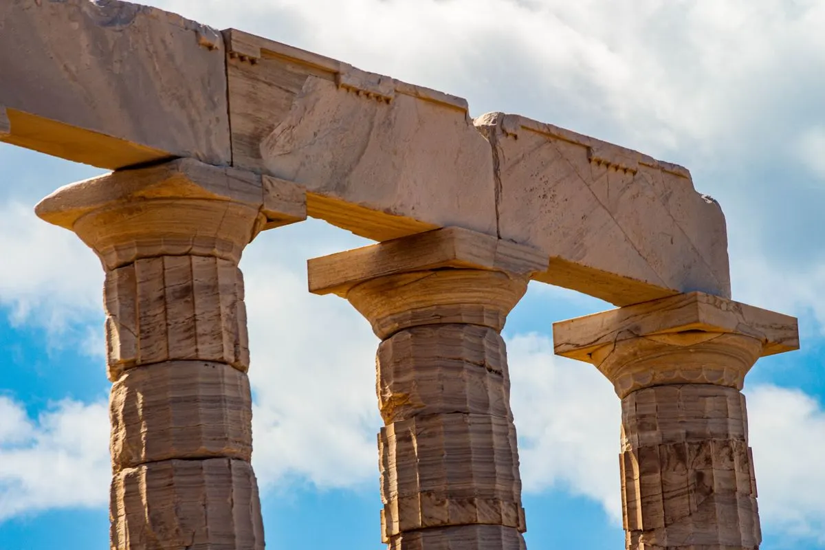 Close-up view of ancient Greek stone columns against a vivid blue sky, highlighting historical…