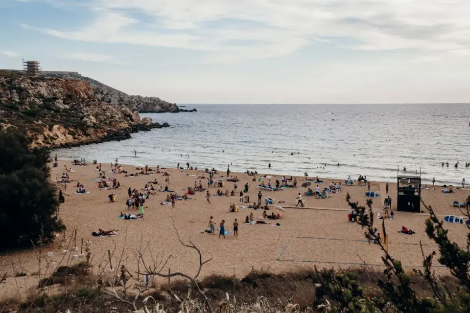 Overhead view of Golden Bay Beach in Malta with people enjoying a summer day by the seaside. -…