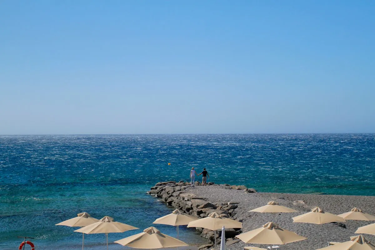 Peaceful beach scene with umbrellas and ocean view under a clear blue sky. - Photo by Сокіл…