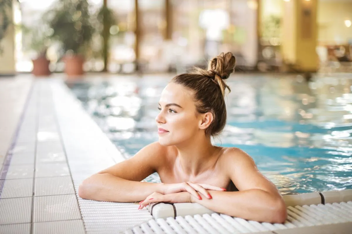 A serene moment as a woman relaxes in a poolside setting at a luxurious resort, enjoying the…