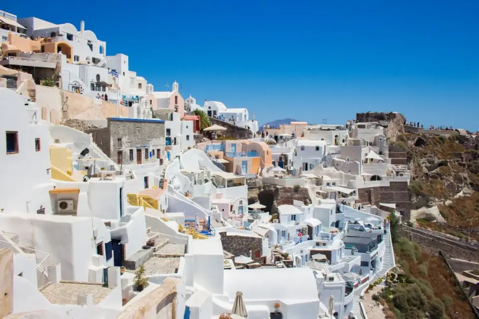 Capture the stunning whitewashed buildings of Santorini, Greece under the bright summer sun. -…
