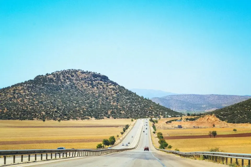 Long straight road through scenic hills under a bright clear sky, perfect for outdoor journeys.…