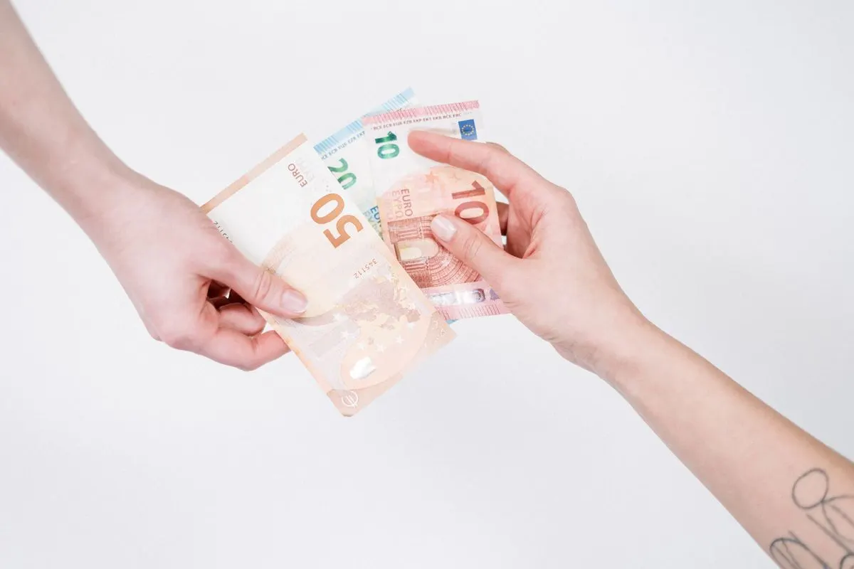 Close-up of hands exchanging euro banknotes, symbolizing financial transactions and currency…
