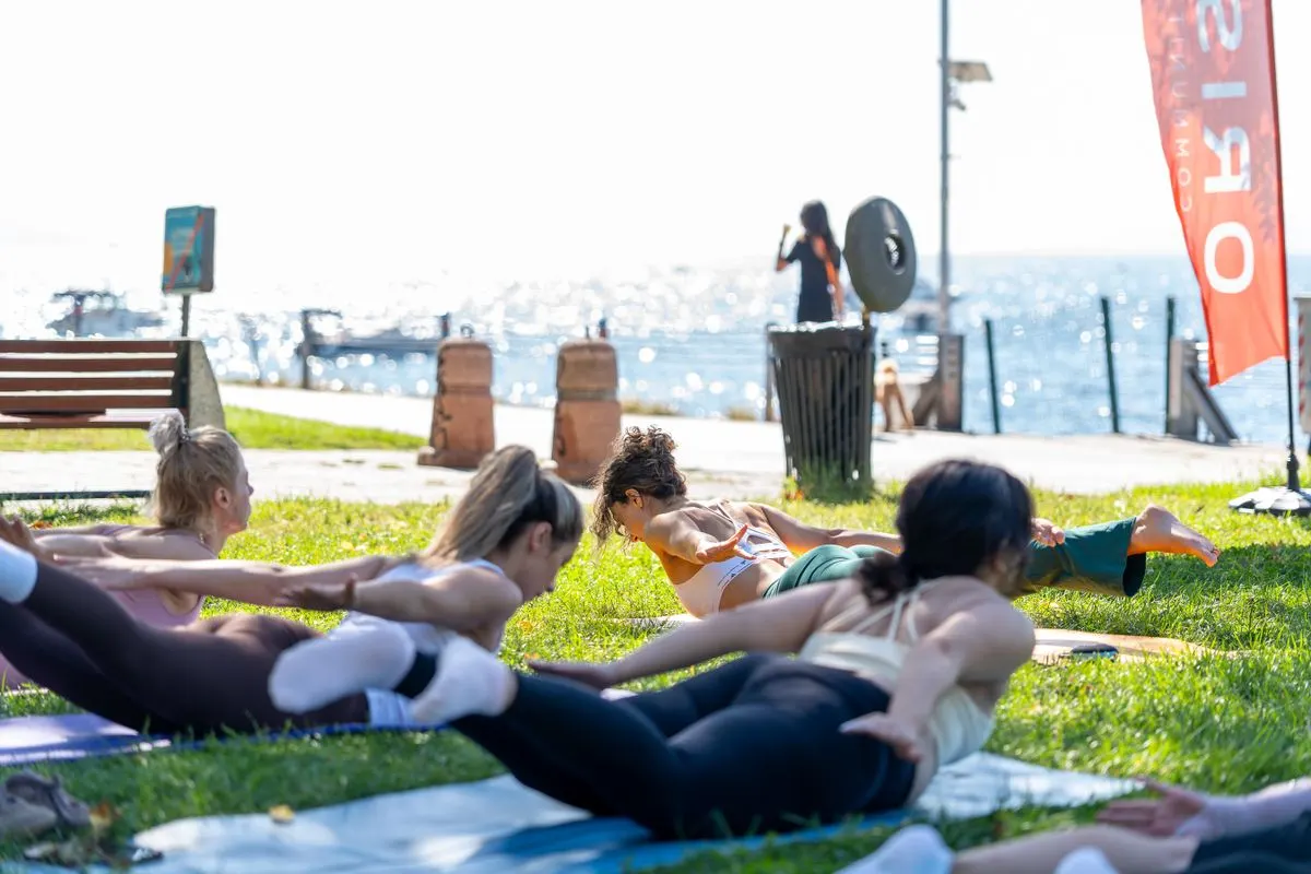 Group of diverse adults practicing yoga outdoors by the sea on a sunny day, embracing fitness…