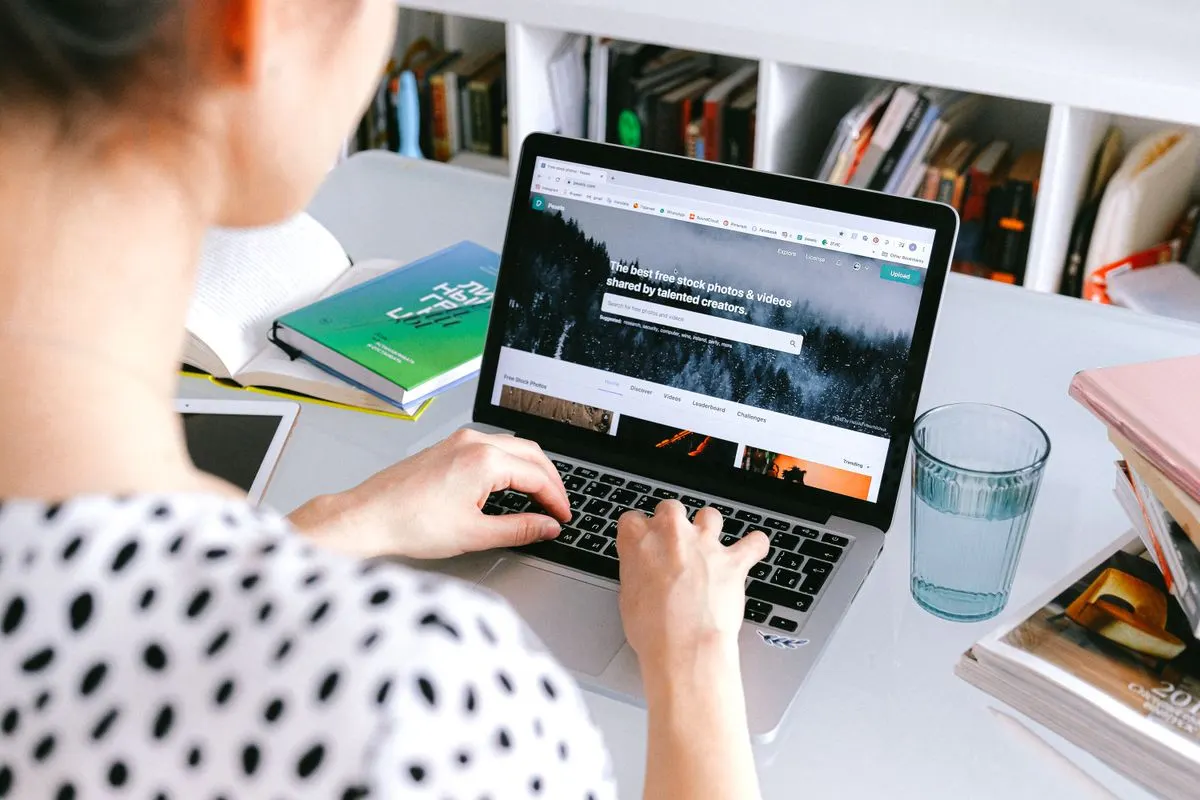 A woman using a laptop at home, browsing stock photos for creative projects. - Photo by Anna…