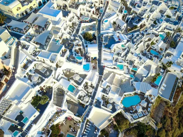 Discover the breathtaking aerial perspective of Santorini's iconic white buildings and pools…