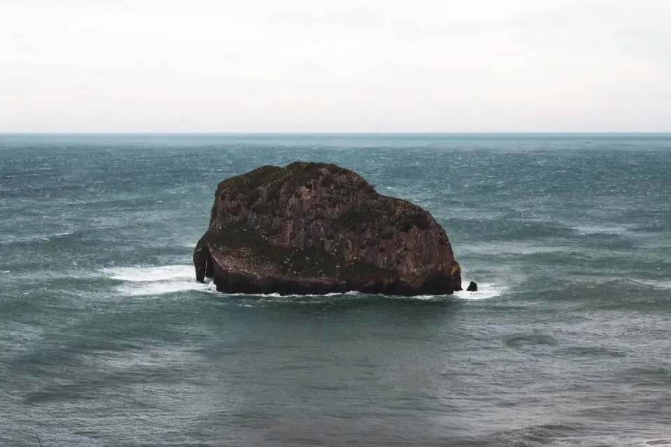 A striking natural rock formation rises from the sea in Donostia-San Sebastián, Spain. - Photo…