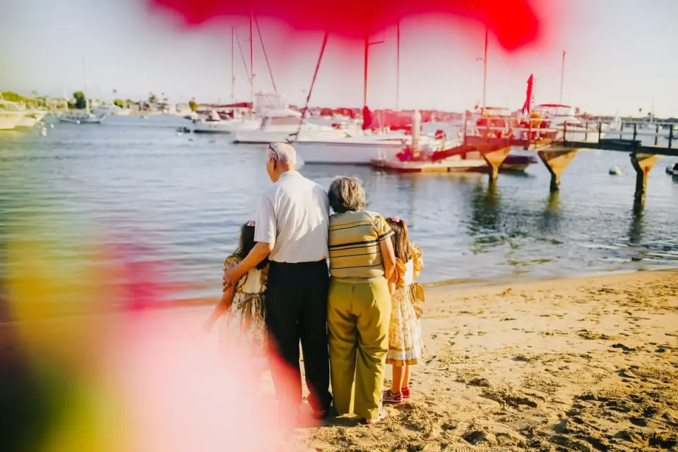 Elderly couple with grandchildren enjoying a sunny day on the beach, overlooking the sea with…