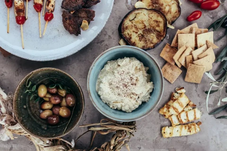 A variety of Mediterranean appetizers featuring hummus, olives, and grilled vegetables set on a…