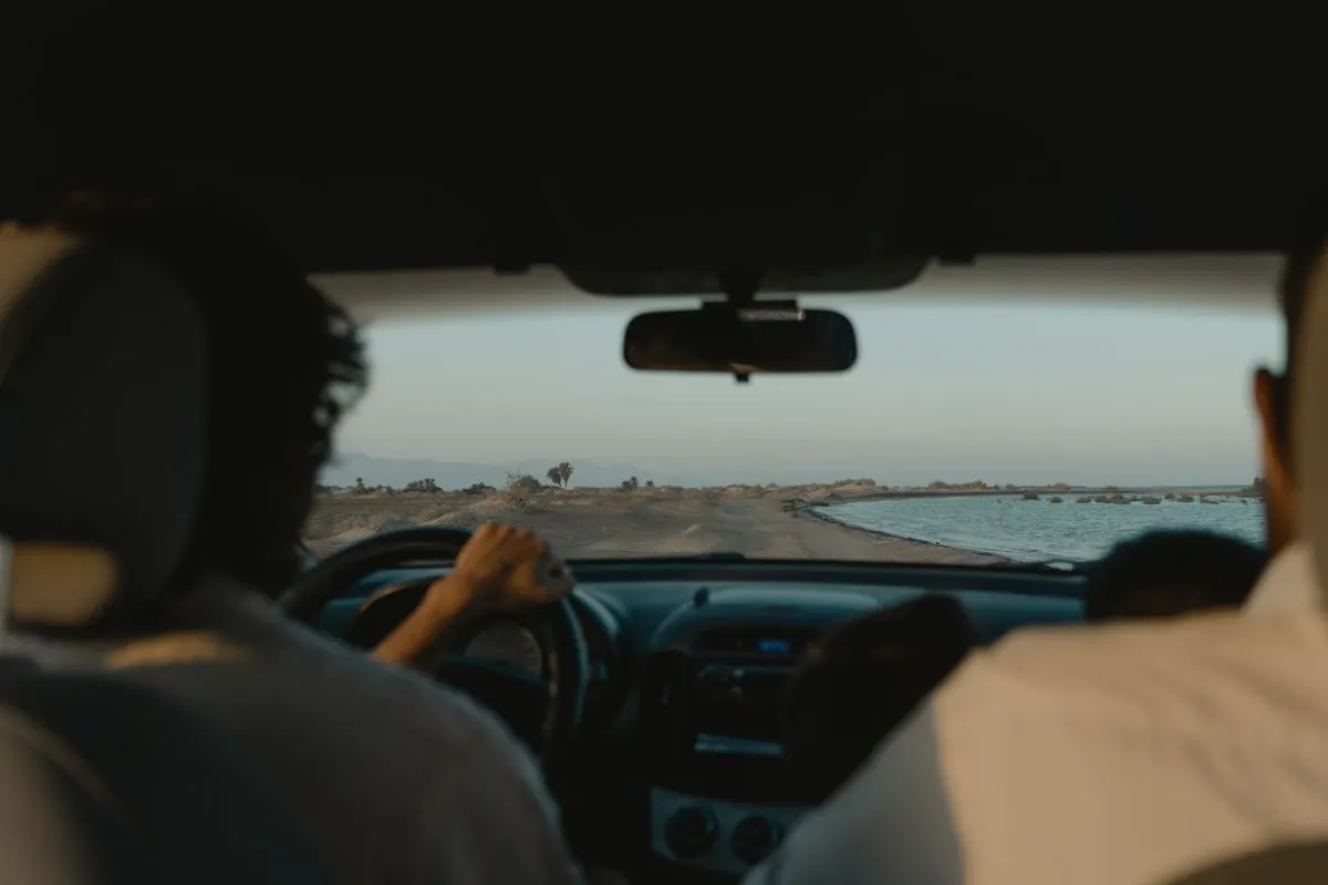 Interior car view of a scenic drive along a coastal road at sunset. - Photo by Tima…