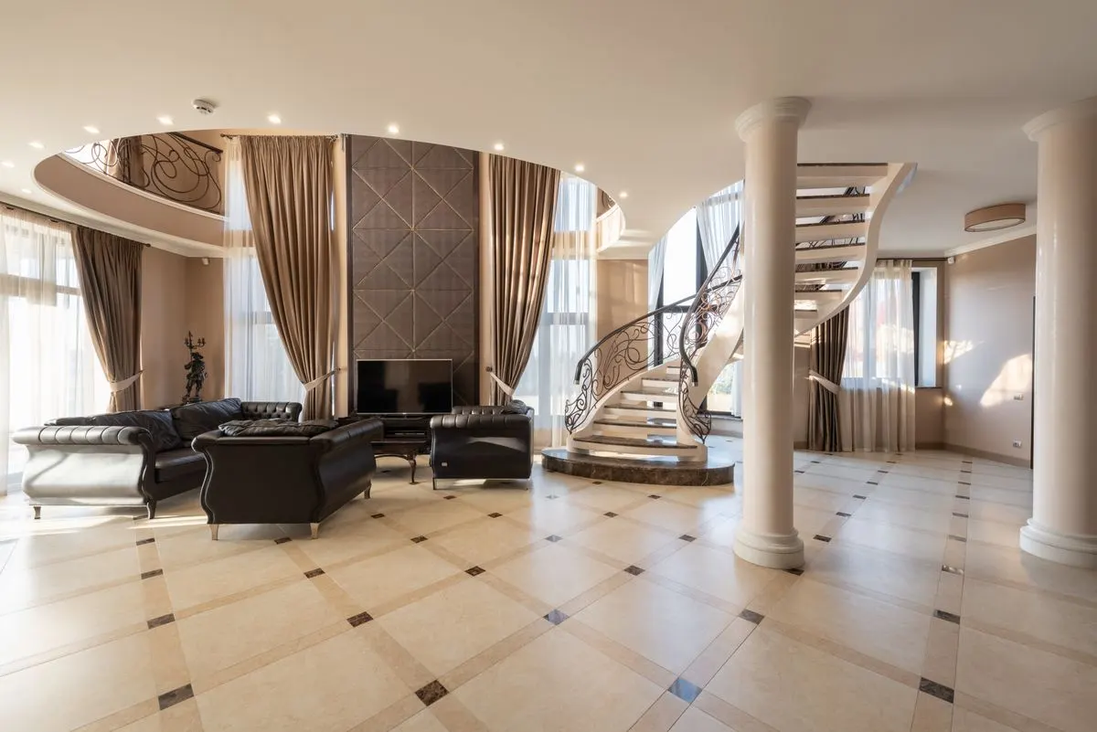 Elegant living room featuring a spiral staircase and classic furniture in a spacious modern…