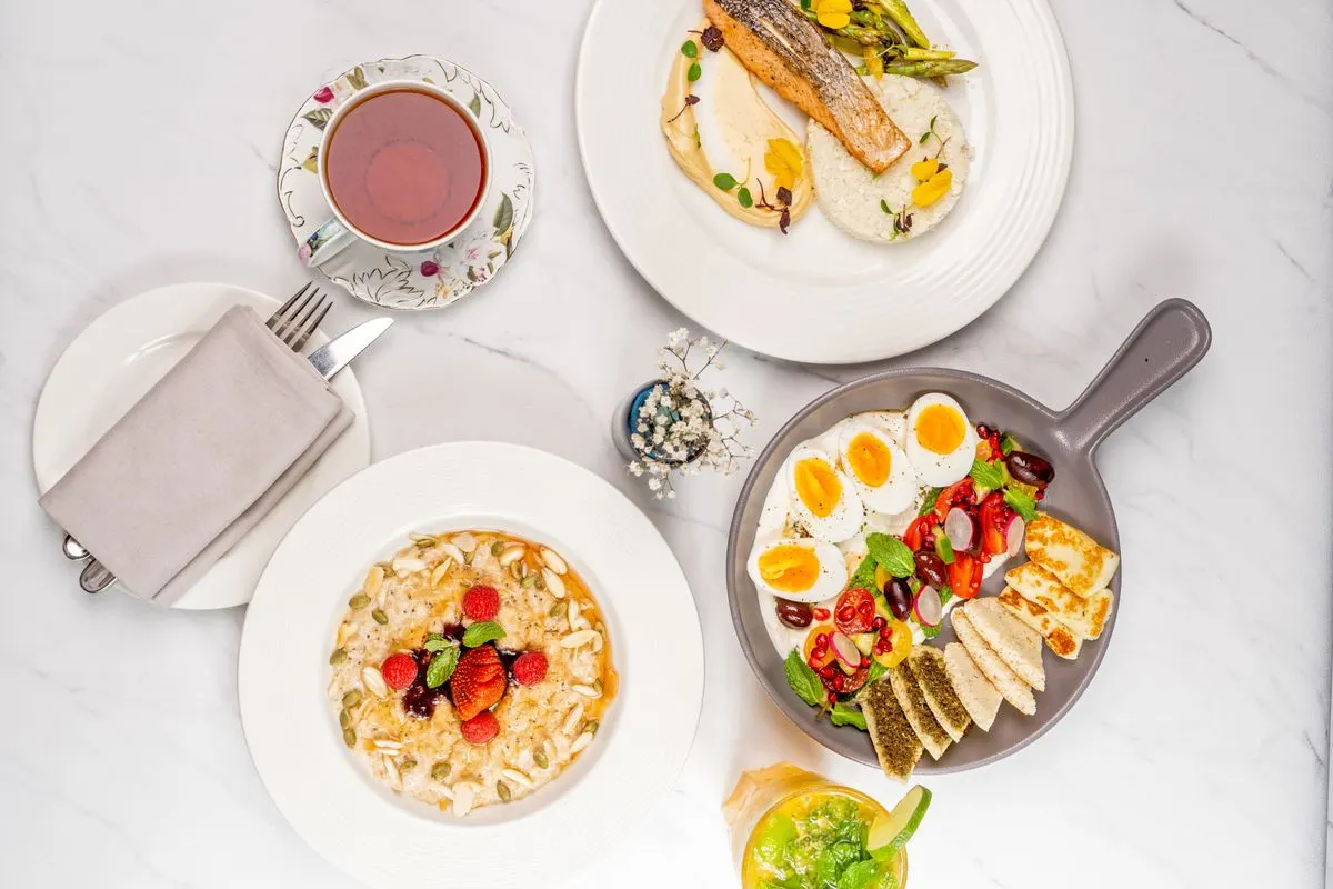 A delectable breakfast spread featuring oatmeal, poached salmon, eggs, vegetables, and tea on a…