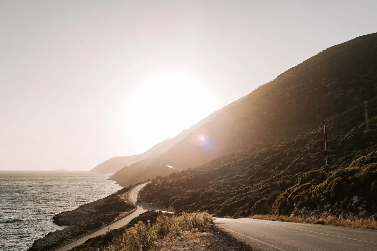Breathtaking view of a coastal road with sunset hues over the ocean and hills in Antalya,…