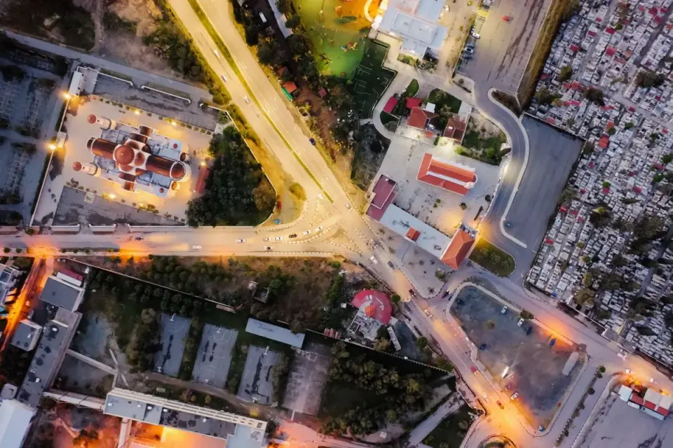 Aerial drone shot capturing a lit cityscape intersection, church, and roads at dusk. - Photo by…