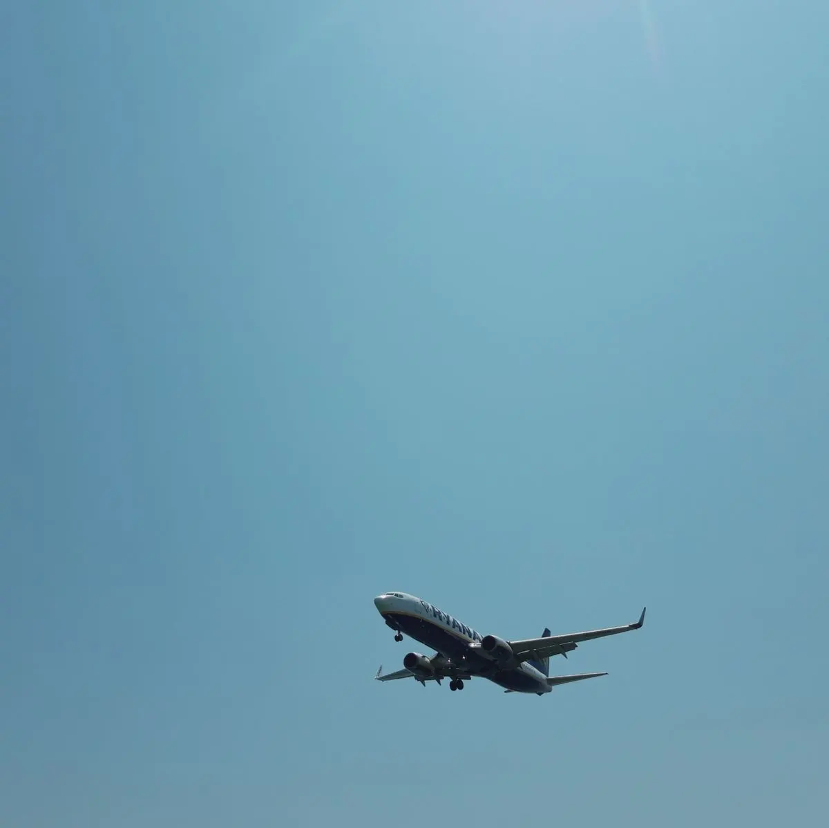 Low-angle view of a commercial airplane flying against a clear blue sky in Corfu, Greece. -…